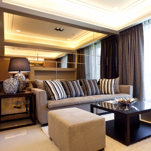 這張照片是現代化的客廳，中間有一張舒適的沙發和一個低矮的咖啡桌，沙發上有柔軟的抱枕，桌子上有裝飾品，呈現出一個放鬆舒適的氛圍。