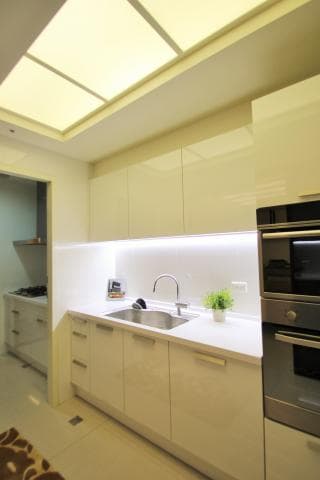 這張照片是一個現代化的廚房，其中最重要的是一個白色的流理台，上面有一個水槽，水槽旁邊是兩個櫥櫃。