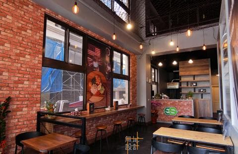 這張「咖啡廳」的照片是一家工業風格的咖啡廳，店內有紅磚牆、木質地板和裸露的燈管，還有幾張桌子和椅子，看起來很舒適。