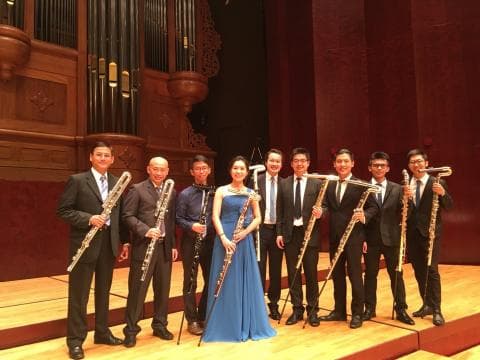 這張「長笛演奏家」的照片是八個音樂家在一個舞臺上，他們每人手持一支長笛，穿著正式服裝，背景是管風琴。