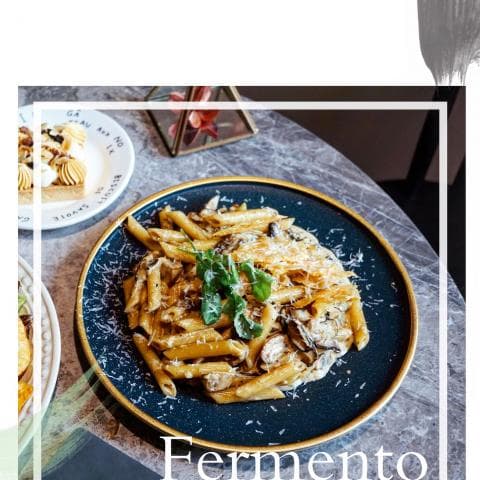 這張照片是一盤義大利麵，上面有蘑菇、奶油醬汁和新鮮香草。