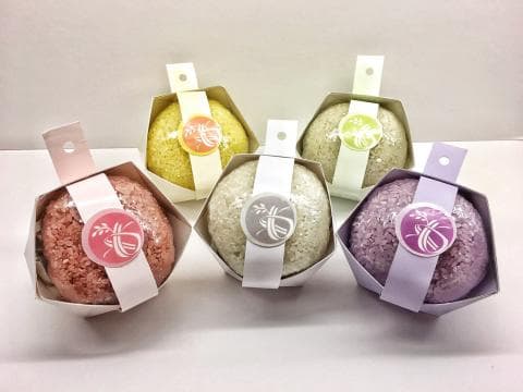 這張「固體洗髮皂」的照片是四種不同顏色的洗髮皂，分別是粉色、黃色、綠色和紫色。每個洗髮皂都有獨特的包裝，上面印有花紋。