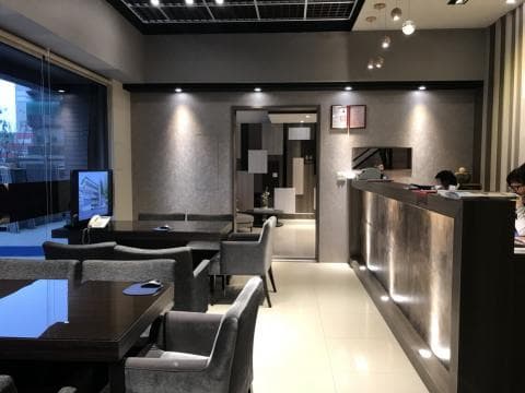 這張照片是一個現代化的接待區，最重要的是櫃檯，櫃檯由木紋材質打造，看起來非常高檔，並設有燈光，讓櫃檯顯得更加明亮，整體設計非常簡潔，讓人感到舒適。