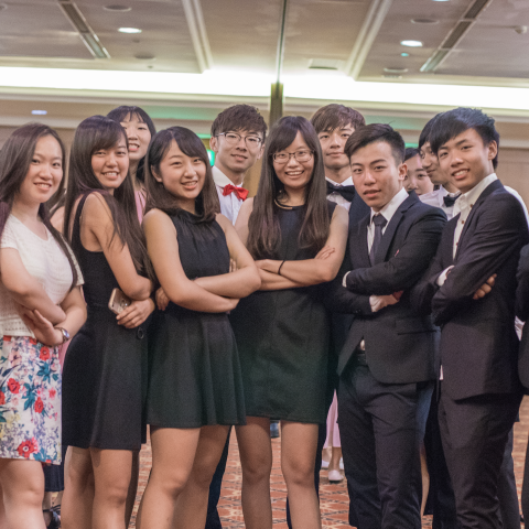 這張「一群朋友聚會」的照片是一個穿著正式服裝的年輕人團體，他們在聚會中微笑並互相拍照。