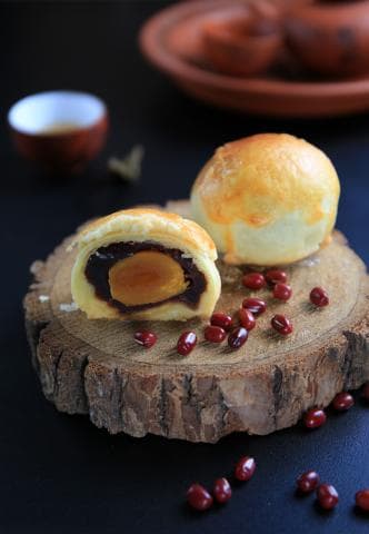 這張「月餅」的照片是 一個切開的月餅，裡面的餡料是紅豆沙和蛋黃，月餅旁邊還有紅豆。