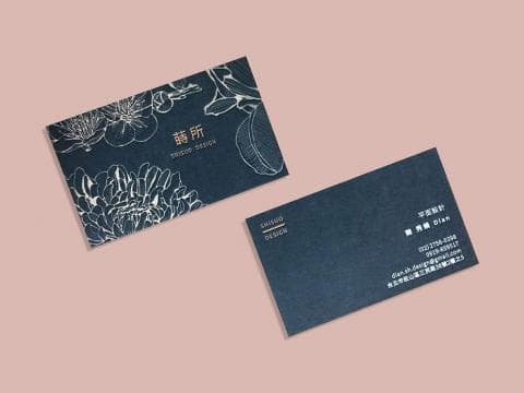 這張照片是一張設計精美的名片，名片上印有白色花卉圖案，背景為深藍色，右上角印有「事務所」字樣和「SHISHO DESIGN」，整體設計風格優雅簡潔。