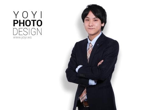 這張「肖像」的照片是，一個穿著西裝，打著領帶的年輕人，雙手交叉放在胸前，背景是白色。