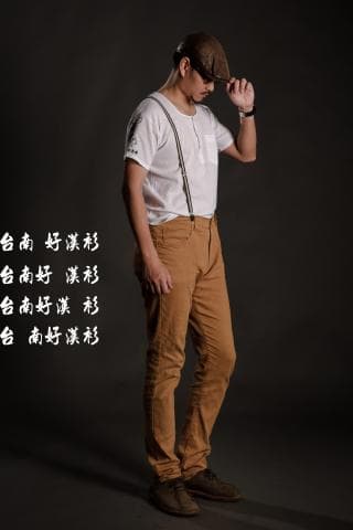 這張照片是一個男人穿著卡其褲，站在灰色背景前。