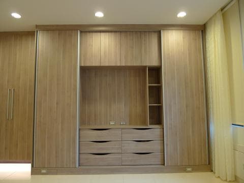 這張照片是一間現代化臥室的衣櫃，主要特色是它由多個木質櫃門和抽屜組成，整體設計簡潔大方，展現出現代風格。