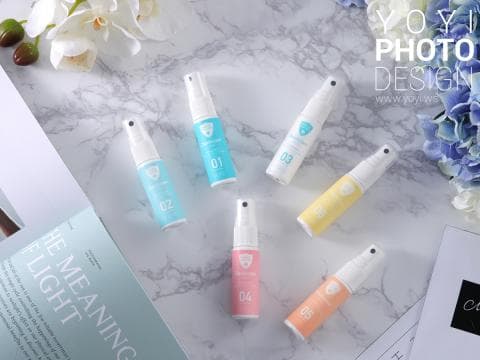 這張「噴霧」的照片是五瓶不同顏色的噴霧瓶放在白色大理石背景上。