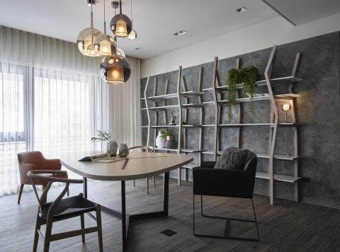 這張「現代風格的餐室」的照片是，有著大型落地窗、木製餐桌、黑色餐椅和灰色書架，其中書架上還放著綠色植物，整體空間明亮舒適。