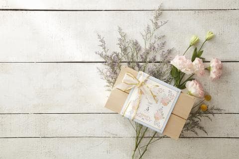 這張照片是一張以木質背景為主的禮品盒照片，禮品盒上綁著緞帶，盒子上還有一張卡片，卡片上印著花朵圖案，整個畫面看起來溫馨浪漫。