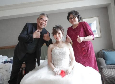 這張照片是一對新人在結婚典禮上，新娘穿著白色的婚紗，新郎和新娘的家人們都面帶笑容，祝福新人幸福美滿。