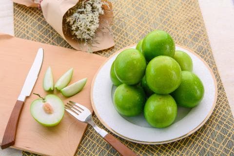 這張「水果」的照片是 一盤青綠色的果實，旁邊放著一個切好的果實和一把刀子。