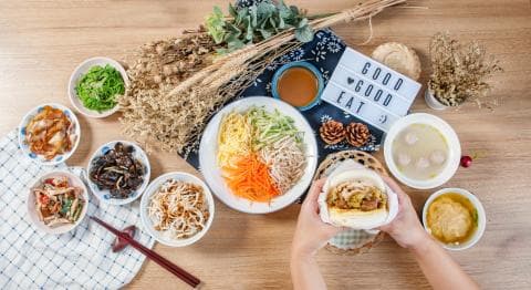 這張「美食」的照片是一張午餐桌，桌上擺著各式各樣的菜餚，包括涼拌菜、肉燥、湯品、以及一個看起來非常美味的漢堡。