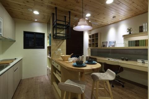 這張「現代化的廚房和用餐區」的照片是，展現了木質裝潢、開放式廚房和簡潔的用餐空間。廚房有木質櫥櫃，用餐區有木質桌椅，並有一盞現代化的吊燈。牆上還裝飾著書籍和照片。