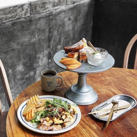 這張「咖啡館」的照片是，桌子上有餐點、咖啡和餐具，以及一個裝飾用的蛋糕架。