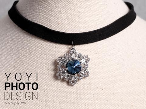 這張「項鍊」的照片是一條黑色天鵝絨項鍊，上面掛著一個鑲著藍寶石和水晶的星形吊墜。