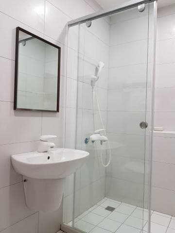 這張照片是一個現代化的浴室，最主要的部分是浴室的淋浴間，淋浴間的玻璃門上有兩個把手，淋浴間的牆壁上裝有一個白色的淋浴頭，淋浴間的地板上有一個白色的地漏。