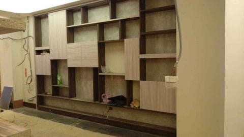 這張照片是一個木質的層架，由多個大小不一的格子和架子組成，看起來像是牆壁的一部分，可以用来放置物品，例如書籍、裝飾品等。