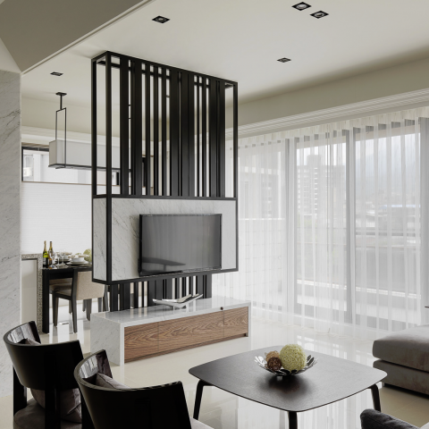 這張照片是一個現代化的客廳，其中最重要的部分是電視牆。牆上裝飾著黑色格柵，中央是大型電視機，下方的木質櫃體也具有現代感。