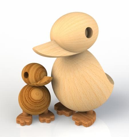 這張照片是一對木製鴨子，一隻大鴨子帶著一隻小鴨子。大鴨子有圓圓的頭和寬扁的嘴，小鴨子則有著圓圓的身體和短小的腳。兩隻鴨子都用木頭製成，表面光滑，看起來很可愛。