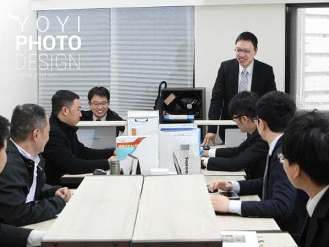 這張「辦公室會議」的照片是幾個男性坐在會議桌旁，他們正在討論工作，其中一位男性站著並指向桌上的文件，他們看起來很專注。