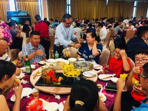 這張照片是一群人在餐桌上聚餐，桌上擺滿了各式各樣的菜餚，看起來非常豐盛。他們看起來都很開心，享受著彼此的陪伴和美食。