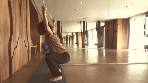 這張照片是一個女性正在做運動，她正在使用一條彈力帶來鍛鍊她的上半身。