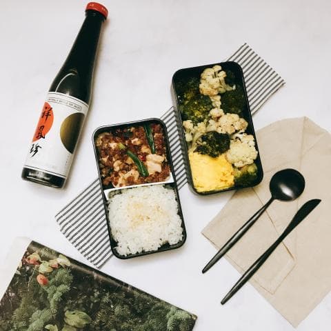 這張照片是一個便當盒，裡面的食物有炒肉絲、白飯和青菜。