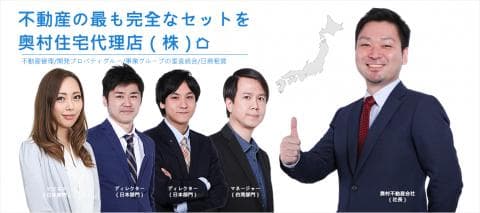 這張「不動產」的照片是四位身穿西裝的年輕男性，其中一位男性站在日本地圖前，並舉起右手比出讚的手勢，另外三位則站在他身後。他們似乎是這間公司的員工，正對著鏡頭微笑。