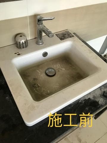 這張照片是一個裝修前的水槽，水槽上有一台水龍頭，水槽已經鋪上白色的瓷磚，但周圍仍然是黑色的水泥。