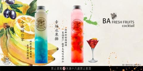 這張「水果酒」的照片是兩瓶水果酒，一瓶藍色，一瓶紅色，旁邊有水果和綠葉的裝飾。
