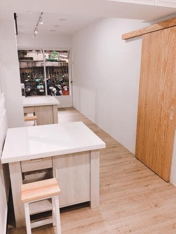 這張照片是一間現代化的廚房，其中最重要的是木製的櫥櫃，它有白色桌面和木質櫃體，並搭配了一張小木凳。