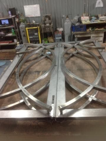 這張照片是一個由金屬製成的圓形框架，中間焊接著兩條金屬條，看起來像是一個大門或窗戶的框架。