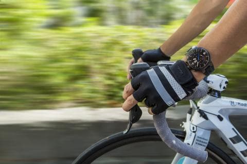 這張照片是 一位騎自行車的人，戴著手套和手錶，手握著自行車的把手。