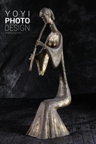 這張「雕塑」的照片是一個金色的女性雕像，她穿著長袍，正在演奏一種樂器。