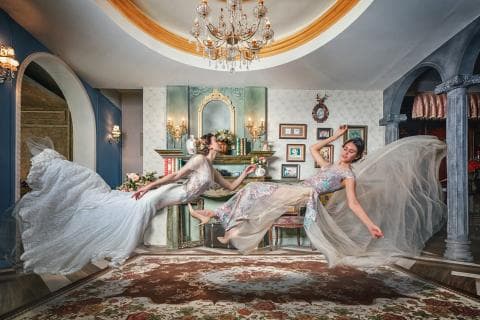 這張照片是兩個穿著禮服的女孩，她們在一個復古風格的房間裡，漂浮在空中，呈現出夢幻的氛圍。