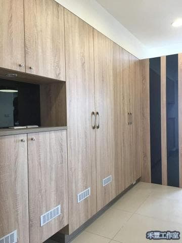 這張照片是一間裝潢精緻的房間，重點是房間的牆面全部以木紋色系的櫃子打造而成，整體風格簡潔又時尚。