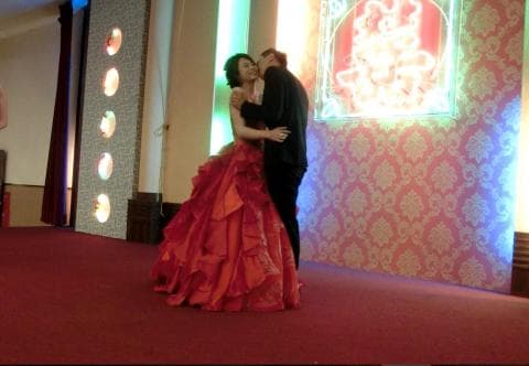 這張婚禮的照片是一對新人正在擁抱，新娘穿著紅色婚紗，新郎穿著西裝。