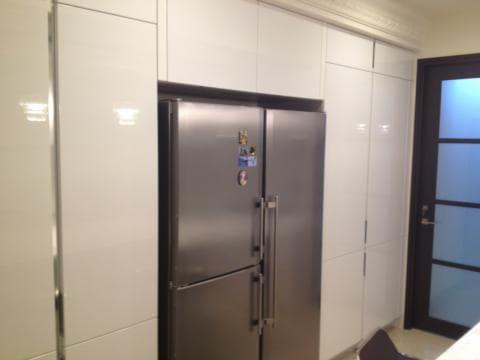 這張照片是一個廚房，最顯眼的是中間的雙門冰箱，銀色的外觀，簡潔的設計，與周圍的白色櫥櫃形成鮮明對比。