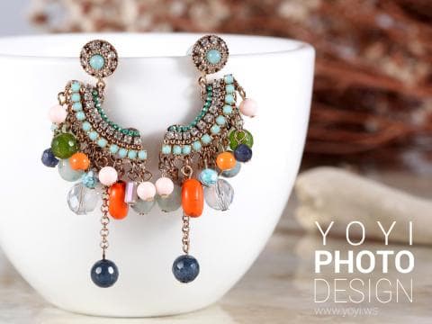 這張照片是一對由許多顏色串珠組成的耳環，耳環上裝飾著許多綠色、橙色和藍色的小珠子，看起來很漂亮。