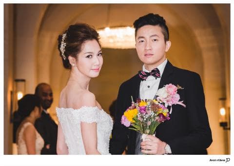 這張「婚禮」的照片是新郎新娘在婚禮現場的合照，新娘穿著白色婚紗，新郎穿著黑色西裝，他們手持花束，笑容滿面。