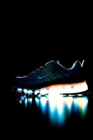 這張「運動鞋」的照片是一雙發光的運動鞋，在黑色背景下顯得格外突出。