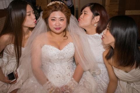 這張照片是三個女人在婚禮上，中間的女人穿著白色婚紗，兩旁的女人穿著白色禮服，她們都看起來很開心。