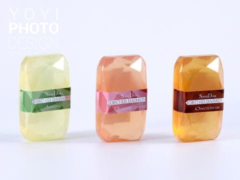 這張「三塊香皂」的照片是三種不同香味的香皂，每塊香皂都有不同的顏色和包裝。左邊的香皂是綠色包裝，中間的香皂是粉色包裝，右邊的香皂是棕色包裝。每塊香皂上都有「Orchid Daimon」的字樣。