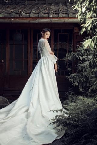 這張照片是一名女子穿著白色婚紗，背景是古色古香的建築，展現出古典與時尚的融合。