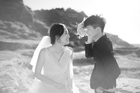 這張照片是一對新人在荒涼的沙漠背景下互相注視，他們臉上洋溢著幸福的笑容，表達出彼此之間的愛與喜悅。