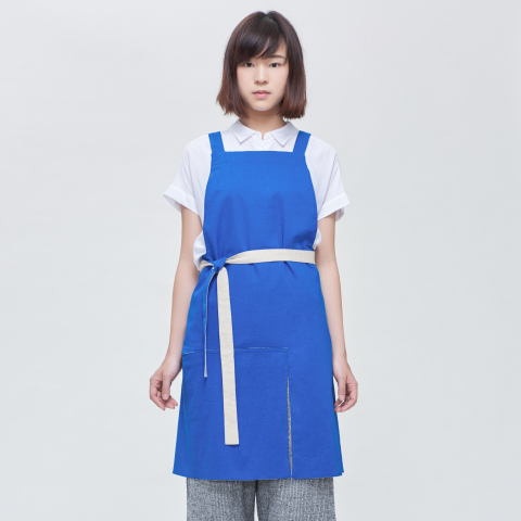 這張照片是一個穿著藍色圍裙的女孩。圍裙上有白色腰帶，圍裙是深藍色。