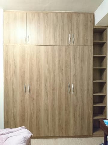 這張照片是一個木製衣櫃，它有六個門和一個開放式的層架。衣櫃的門上都有銀色的把手，層架上放了一些物品。